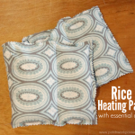 Two rectangular fabric rice heating pads with a blue and gray patterned design are placed on a wooden surface. The image text reads: "Rice Heating Pad with essential oils—see how to sew a microwave heating pad for soothing warmth.