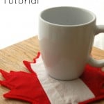 A white mug rests on a red and white maple leaf-shaped coaster on a wooden surface. The text reads "Maple Leaf Mug Rug Tutorial," inviting you to explore free mug rug patterns perfect for quilting enthusiasts.