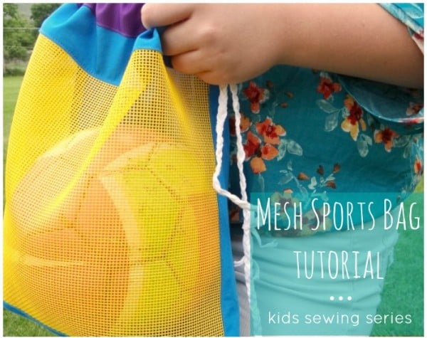 mesh sports bag held by a girl standing in the grass. the bag is closed but has a soccer ball that you can see in the mesh