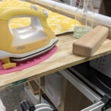 oliso iron and clapper on a wood iron board that is laid on a long arm bars