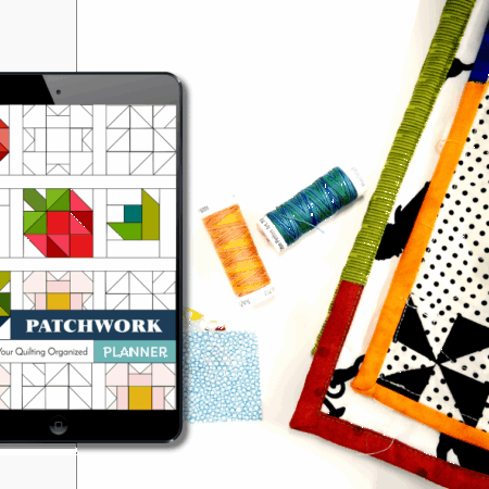 digital patchwork planner on an ipad screen next to thread and quilts on a table