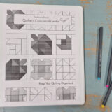 A binder labeled "Quilter's Command Center" with 2026 quilting patterns on the cover sits on a distressed blue surface next to three colored pens: black, blue, and pink.
