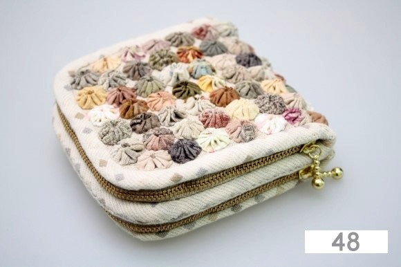 A square beige fabric coin purse with two zippers and a pattern of small, colorful, textured Fabric Yo-Yo rosettes on top. The number 48 is displayed in the bottom right corner.
