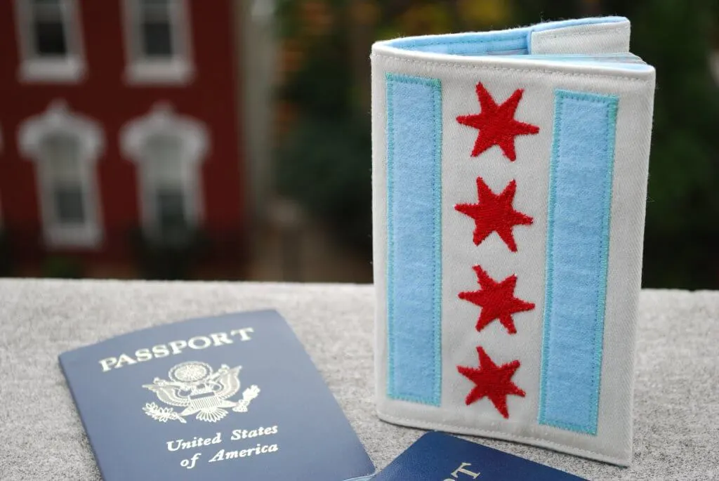 10 Patriotic Flag Projects to Sew Before the 4th of July 7 A U.S. passport and a passport cover with the Chicago flag design, perfect for Patriotic flag projects, featuring blue stripes and four red stars, are displayed on a ledge with a blurred building in the background.