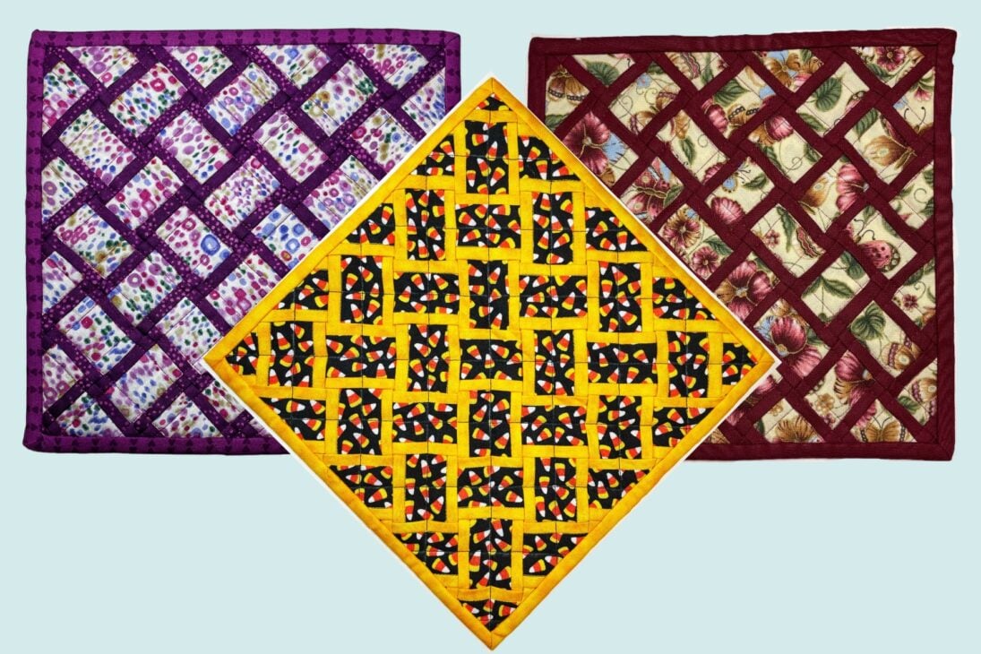 Three colorful quilted pot holders are displayed. The left one features purple fabric with a lattice design, the center is yellow with a crisscross pattern, and the right is red with a floral motif and maroon borders.