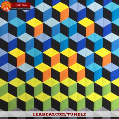 25 Must Sew Scrappy Strip Quilt Patterns 16 A vibrant, geometric pattern of interlocking 3D cubes in blue, yellow, orange, and black—reminiscent of scrappy strip quilt patterns. "Leah Day" and a website link appear at the top and bottom of the design.