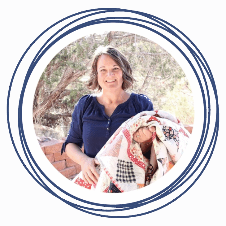 A woman with shoulder-length brown hair, wearing a navy blue shirt, stands outdoors holding a colorful patchwork quilt. She is smiling, framed by circular blue lines and trees, ready to Move the Needle at the upcoming Quilting Summit.