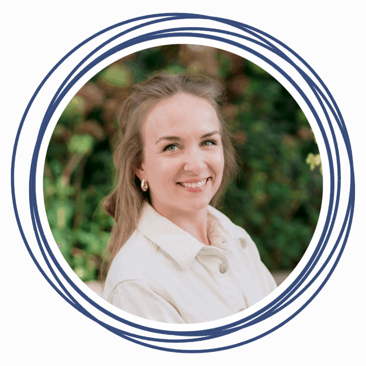 A woman with light brown hair, wearing a cream-colored jacket and gold hoop earrings, smiles at the camera. She is framed by overlapping blue circles, reflecting the creative spirit of a quilting conference, with a blurred green outdoor background.