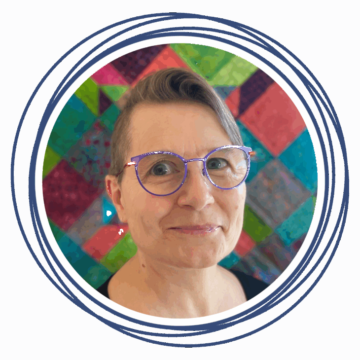 A person with short, side-swept hair and purple glasses smiles gently. They are in front of a colorful, patchwork quilt background&mdash;perfect for any quilting summit&mdash;framed by hand-drawn navy blue circular lines.