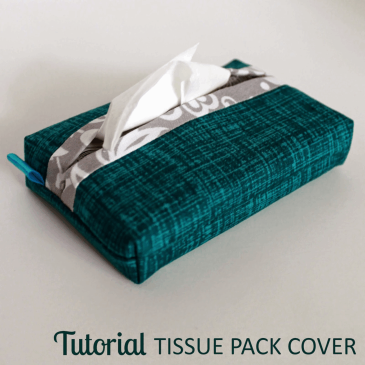 A teal fabric tissue pack cover with a gray and white patterned strip, holding a tissue partly pulled out. The text "Tutorial TISSUE PACK COVER" appears at the bottom, perfect for learning to sew travel tissue holder patterns.