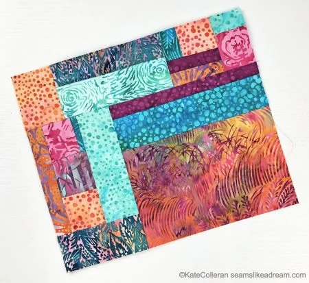 A colorful quilt block made from various patterned fabric strips in shades of orange, pink, teal, blue, and purple, arranged in a geometric pattern&mdash;perfect inspiration for crumb quilt ideas.