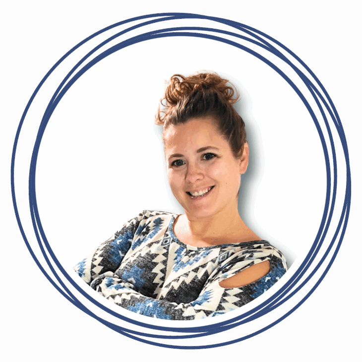 A smiling woman with curly hair tied up, wearing a blue and white patterned top with cut-out shoulders, stands with arms crossed inside a double blue circular border&mdash;ready to move the needle at the quilting summit.