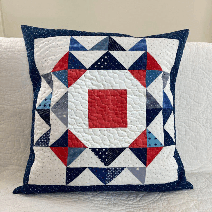 250th Anniversary Pattern Bundle - Limited Time 16 A decorative throw pillow features a colorful quilted Anniversary Pattern with a red square center, surrounded by geometric designs in red, white, blue, and navy, set against a white background with a navy blue border.