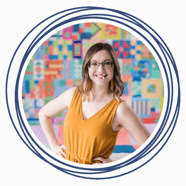 A smiling woman with glasses and shoulder-length hair stands in front of a colorful patchwork quilt, wearing a sleeveless mustard-yellow top&mdash;ready to move the needle at the upcoming quilting summit. The image is framed by concentric blue rings on white.
