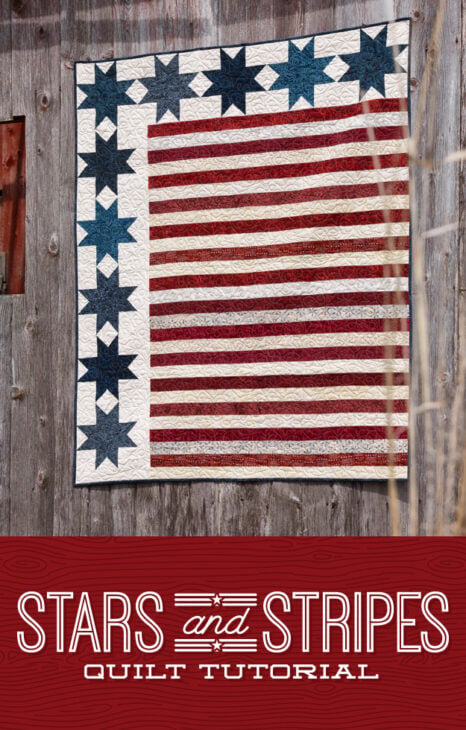 A quilt inspired by the American Flag, featuring blue stars on a white background and red and white stripes, hangs on a rustic wooden wall. Text below reads, "Stars and Stripes Quilt Tutorial.