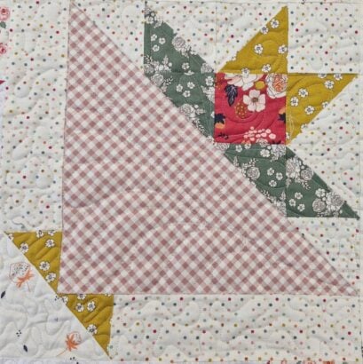 A quilt block for the June 2026 BOM, featuring a pink and white gingham triangle, floral green and yellow triangles, and a white background with colorful dots and small orange flowers in a geometric basket pattern.