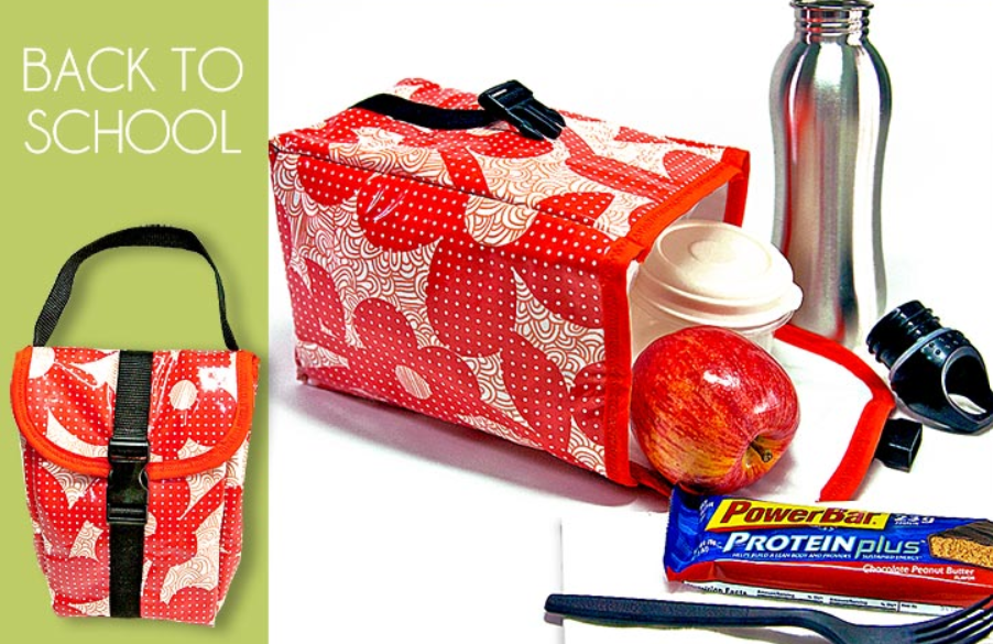 Easy and Cute Lunch Bag Sewing Patterns You'll Want to Make and Use 6 A red patterned lunch bag with a strap and buckle, cup, apple, water bottle, PowerBar, and straw sits next to text reading "BACK TO SCHOOL" on a green background, promoting back-to-school supplies. Discover cute lunch bags inspired by easy sewing patterns—perfect for making this school year organized and stylish.