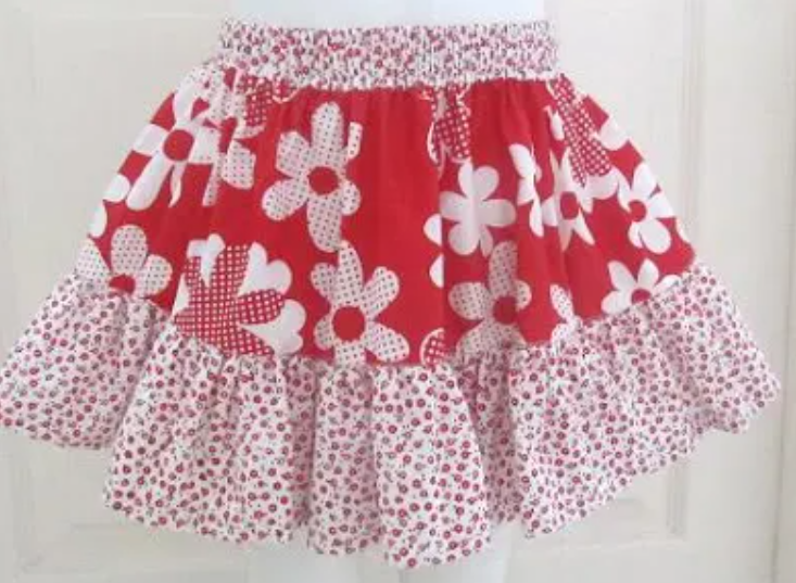 15 Easy Elastic Waist Skirt Patterns You Can Sew Today (All Free) 8 A red and white skirt with large white flowers on the top section and a ruffled hem featuring small red floral patterns along the bottom—perfect inspiration for those searching for easy skirt patterns or classic elastic waist skirt patterns.
