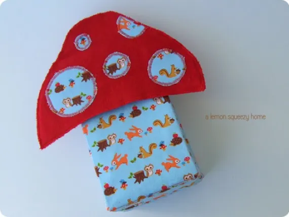 Easy and Cute Lunch Bag Sewing Patterns You'll Want to Make and Use 2 A soft fabric mushroom toy with a red cap decorated with blue patches featuring owls, squirrels, and mushrooms—perfect inspiration for cute lunch bag patterns. The stem is blue with similar animal prints, making it an adorable muse for your next lunch bag sewing patterns project.
