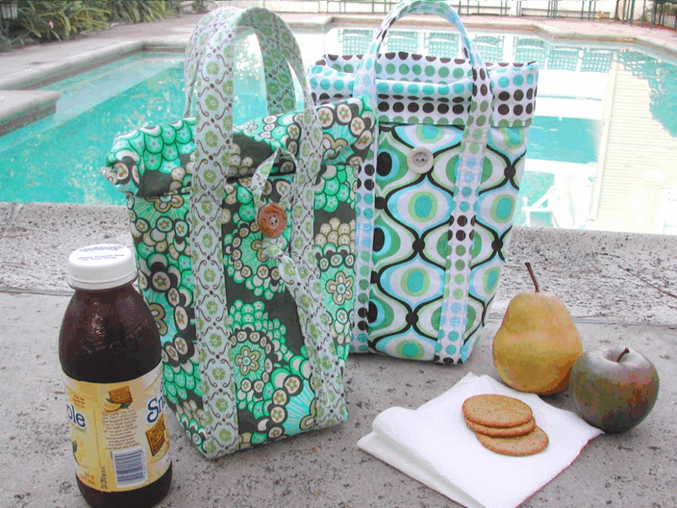 Easy and Cute Lunch Bag Sewing Patterns You'll Want to Make and Use 11 Two patterned fabric lunch bags—crafted from easy sewing patterns—sit beside a pool, along with a bottle of tea, a pear, an apple, and four crackers on a napkin. The scene suggests a casual outdoor picnic with cute lunch bag designs adding charm to the setting.