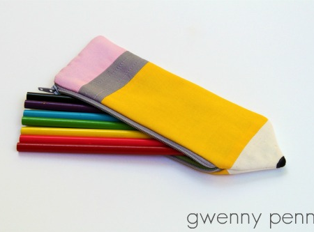 A pencil-shaped zippered pouch contains six colored markers (green, blue, black, yellow, red, and pink) on a white background. Perfect for those who love to make their own accessories, this Pencil pouch is a fun project idea inspired by sewing patterns. The words "gwenny penny" appear in the bottom right corner.