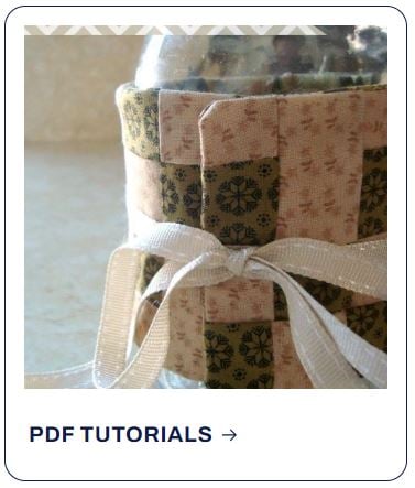 A fabric mug cozy made of small, patterned quilt squares that coordinate with our shop patterns, tied with a white ribbon.